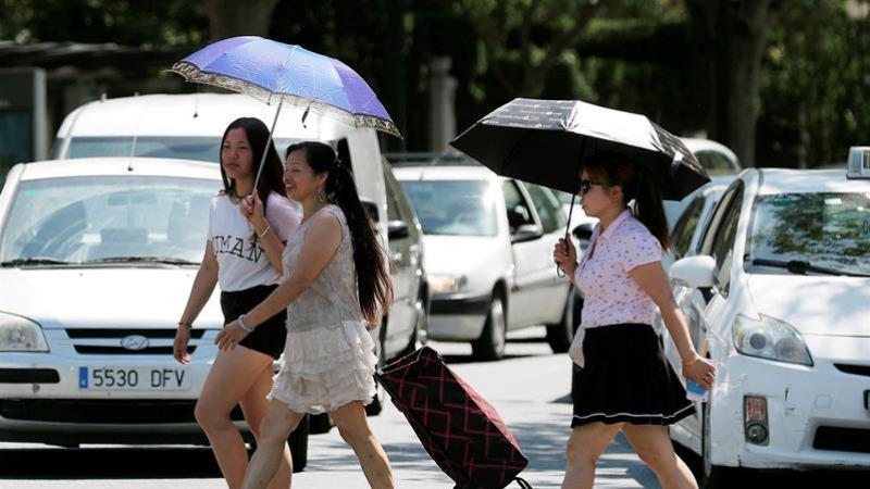 Tres mujeres se protegen del sol y del calor con sombrillas. /EFE
