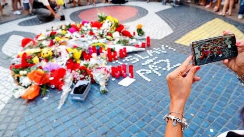 16/08/2019 - Una turista fotografía los ramos de flores y objetos de todo tipo depositados en el mural de Miro de La Rambla de Barcelona en recuerdo de los atentados en La Rambla y Cambrils. - EFE/Alejandro García