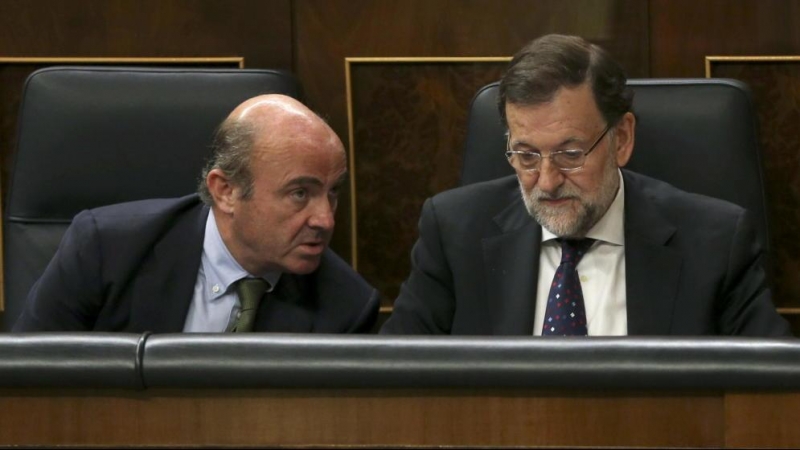 El equipo económico de Rajoy, con Luis de Guindos a la cabeza, siempre sostuvo que el rescate no iba a costarle dinero al Estado. En la imagen, el entonces ministro de Economía con el presidente del Gobierno en el Congreso de los Diputados. EFE