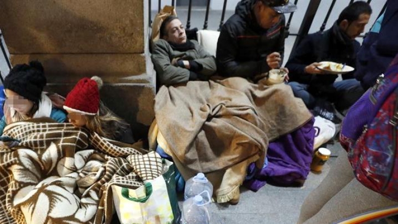 Solicitantes de asilo que esperan un recurso de acogida frente a las puertas del Samur Social de Madrid. EFE/Javier Lizón
