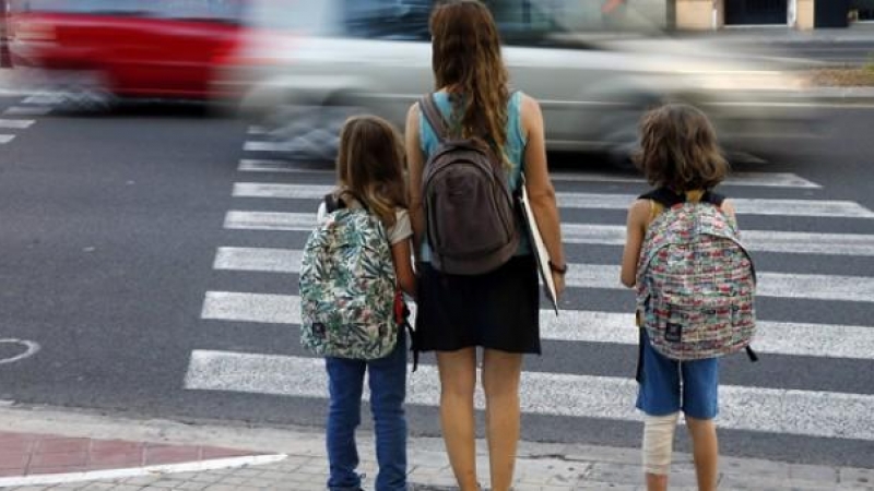 Una madre y sus hijas esperan a que los coches pasen para poder cruzar cuando van de camino a la escuela./ EFE-Archivo