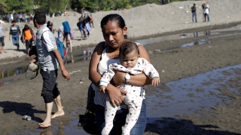 Migrantes de la caravana que viaja a Estados Unidos cruzando a la orilla guatemalteca del río en Ciudad Hidalgo, México. / Reuters