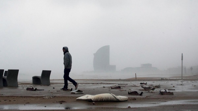 21/01/2020.- Una persona camina por la playa de la Barceloneta, en Barcelona durante el temporal. / EFE - ENRIC FONTCUBERTA