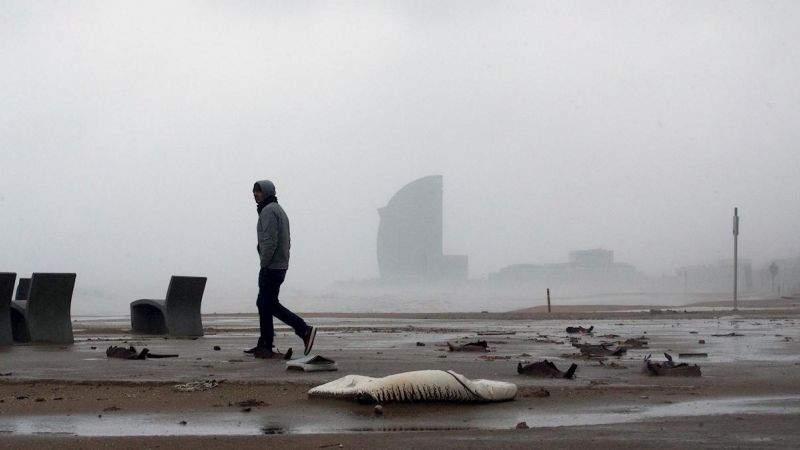 21/01/2020.- Una persona camina por la playa de la Barceloneta, en Barcelona durante el temporal. / EFE - ENRIC FONTCUBERTA