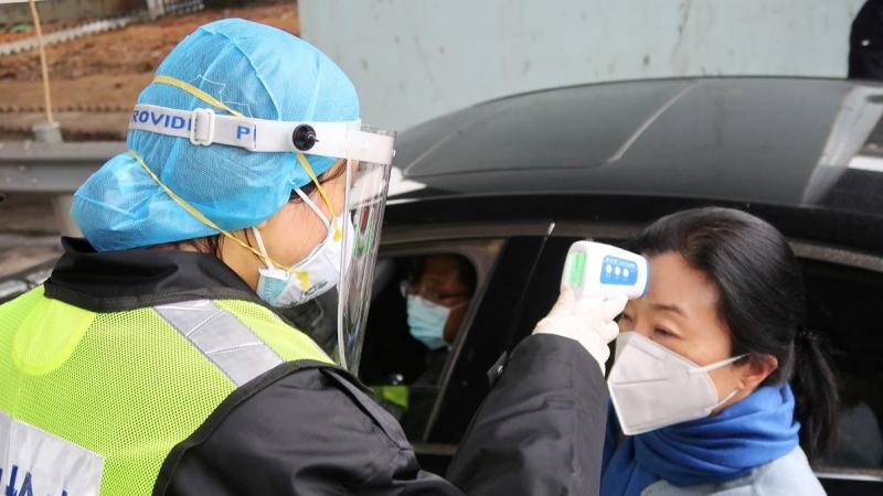 Un oficial de seguridad toma la temperatura a una pasajera tras el brote del coronavirus. REUTERS