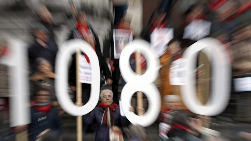 Jubilados y pensionistas sostienen carteles con la cifra 1080 euros, cantidad que demandan como pensión mínima los jubilados y pensionistas a la administración, durante la concentración para reivindicar unas pensiones públicas dignas, este lunes en Bilbao