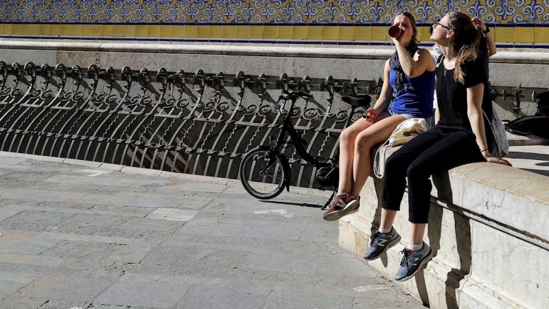 Dos turistas disfrutan del sol en València. (MANUEL BRUQUE | EFE)