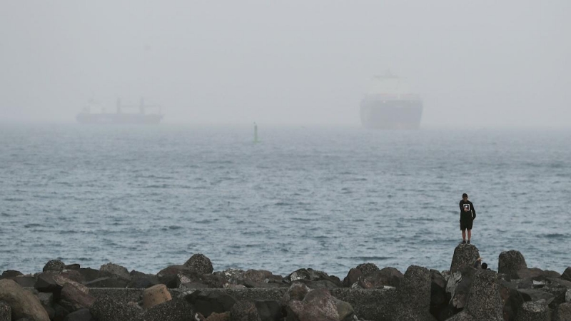 Un joven observa dos barcos que se adivinan en la bahía de Las Palmas de Gran Canaria. EFE/Elvira Urquijo A.