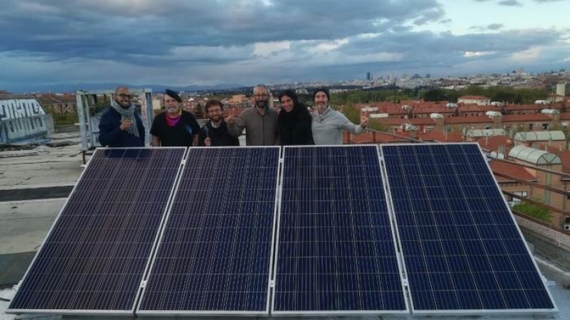 Activistas del EKO de Carabanchel junto a una placa fotovoltaica en su azotea.