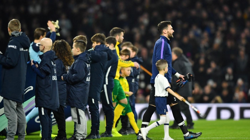 Un niño acompañando al portero y capitán del Tottenham Hotspur, Hugo Lloris. / Reuters