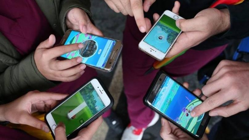 Vista de un grupo de gente jugando con sus teléfonos móviles. EFE/Archivo