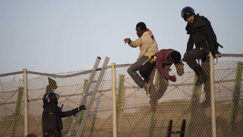 Varios inmigrantes subsaharianos tratan de cruzar la valla fronteriza de Melilla.-  REUTERS/ARCHIVO