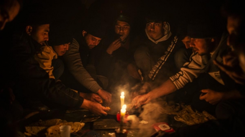 Migrantes afganos cenan en el interior de un edificio abandonado donde están viviendo en Bihac. JM López.