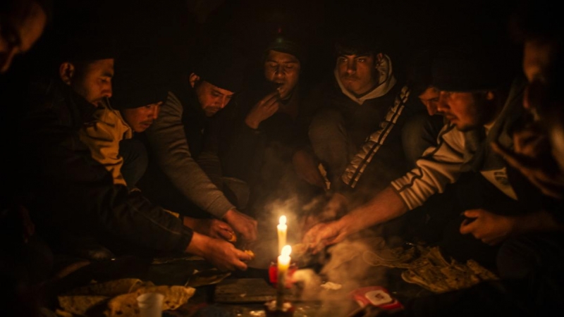 Migrantes afganos cenan en el interior de un edificio abandonado donde están viviendo en Bihac. JM López.