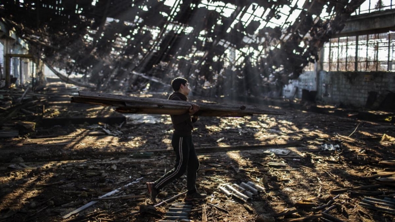 Un migrante afgano recoge madera para hacer una hoguera en una factoría abandonada del polígono industrial de Bihac. JM López.