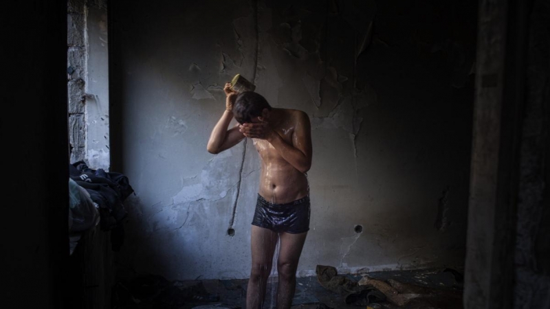 Akram, de 16 años, se ducha en el interior de un edificio abandonado donde esta viviendo junto con otros afganos en Bihac. JM López.