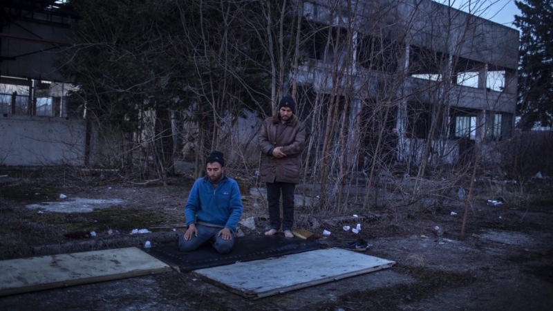 Mohamed, de 29 años, reza junto a un compatriota afgano al lado del edificio abandonado donde están viviendo en Bihac. JM López.