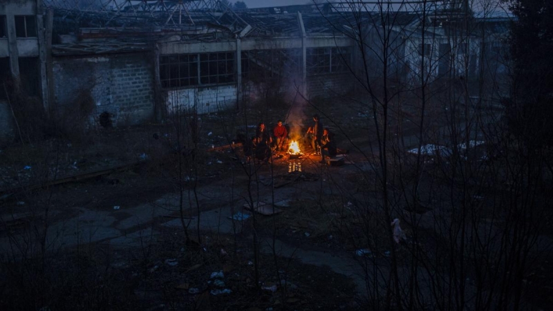 Un grupo de migrantes afganos se calientan en una hoguera al lado de una factoría abandonada del polígono industrial de Bihac. JM López