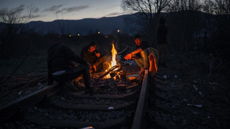 Migrantes se calientan en una hoguera sobre las vías de tren en desuso en el polígono industrial de Bihac. JM López.