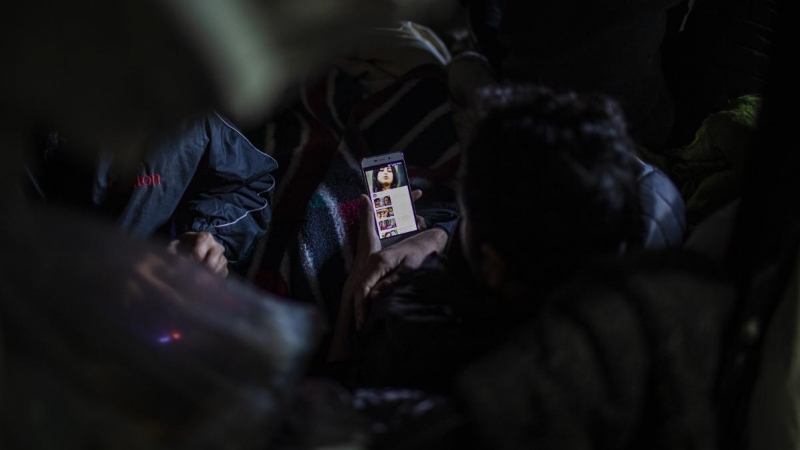 Un migrante de Bangladesh mira una película en su teléfono móvil en una habitación del campo de Miral situado en Velika Kladusa. JM López.