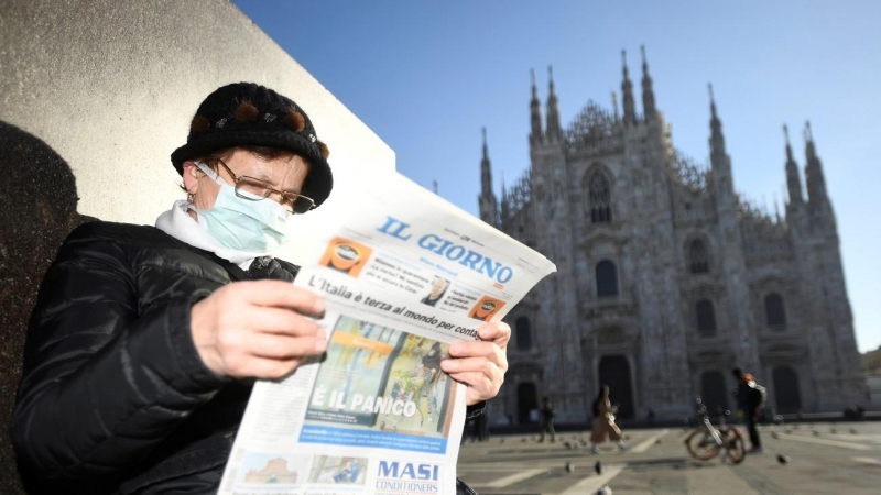 24/02/2020- Una mujer con mascarilla lee el diario 'Il Giorno' frente a la catedral de Milan (Italia). / REUTERS