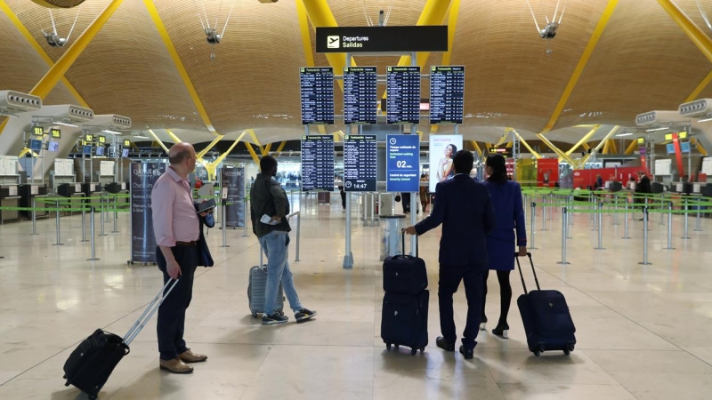 Varios pasajeros miran los paneles informativos de los vuelos en el aeropuerto de Barajas, en Madrid.. REUTERS/Susana Vera