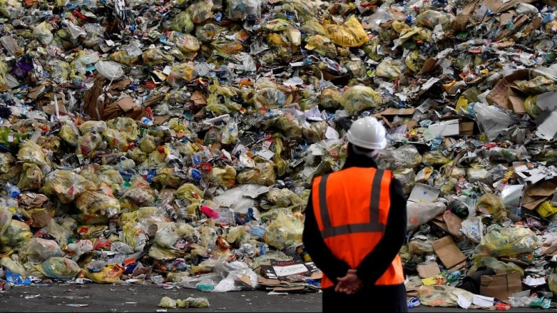 Un operario observa parte de los residuos prensados en una planta de reciclaje. /AFP