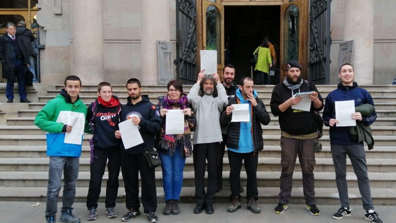 Alguns dels encausats per seure a les escales del TSJC mostren la sentència absolutòria a les portes del tribunal. Alerta Solidària