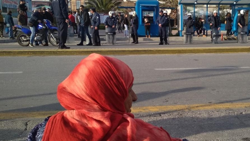 Una mujer al lado de la parada del bus, observando a la policía, Mitilini, Lesbos.