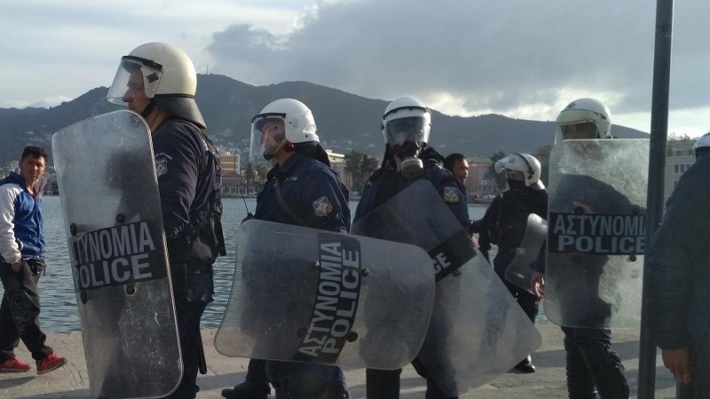 Policías griegos cargan contra los refugiados en el puerto de Mitilini.