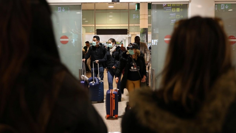 Pasajeros con mascarilla procedentes de Italia llegan al aeropuerto de Barcelona. - REUTERS