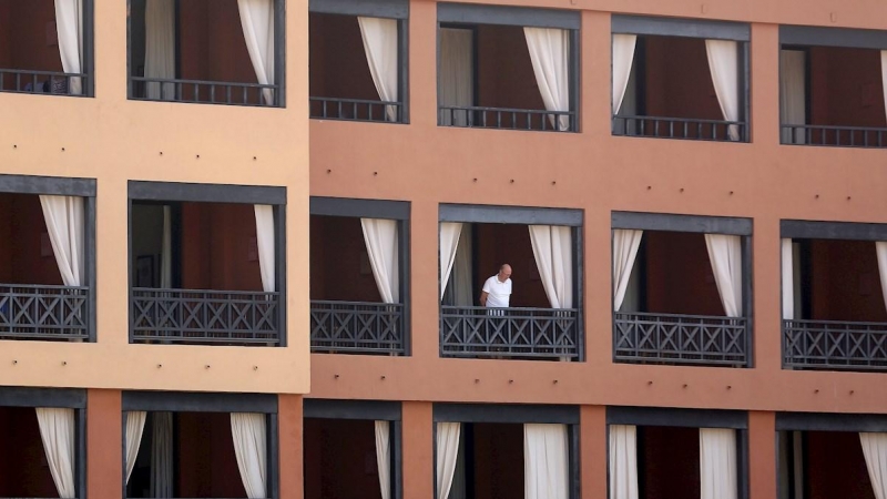 Un turista se asoma desde el balcón de su habitación en el hotel del sur de Tenerife. - EFE