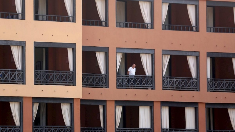 Un turista se asoma desde el balcón de su habitación en el hotel del sur de Tenerife. - EFE