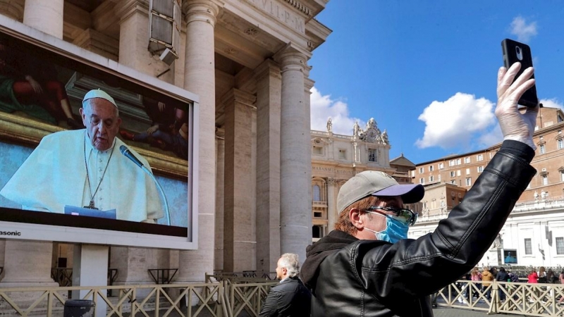 Un turista se saca una foto frente a una de las pantalla gigante instalada en la plaza del Vaticano para la misa del ángelus./ RICCARDO ANTIMIANI (EFE/EPA/ANSA)