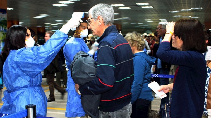 Operarios sanitarios toman la temperatura a los pasajeros en el aeropuerto internacional de Luxor. - EFE