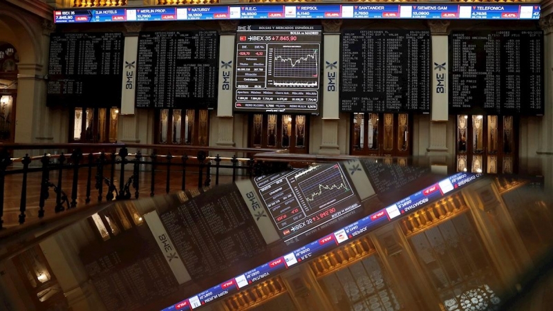 Una pantalla (al fondo) muestra un gráfico con la evolución del IBEX 35 en la Bolsa el pasado lunes. - EFE