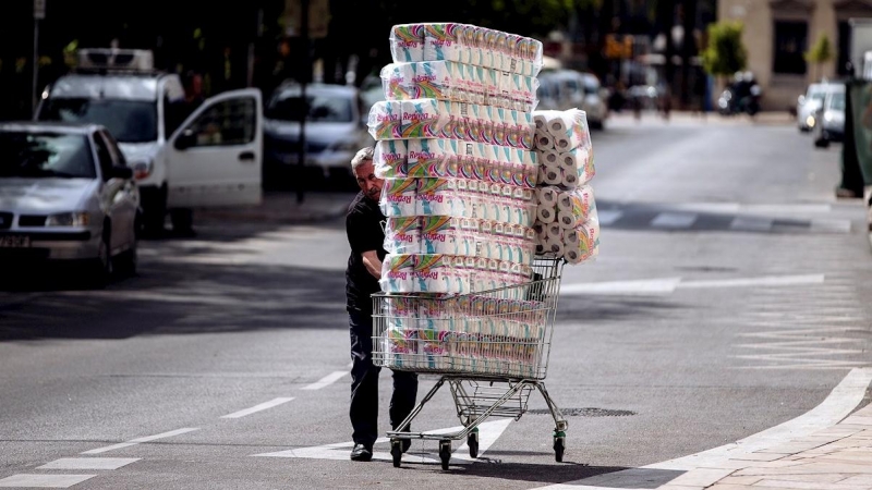 Un trabajador transporta numerosos rollos de papel higiénico en un carro de la compra dirección a un comercio en el centro de Málaga. - EFE