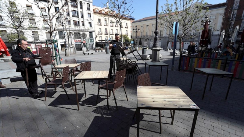 Varias personas recogen este viernes la terraza de un bar en la Plaza de Santa Ana, en el centro de Madrid. - EFE