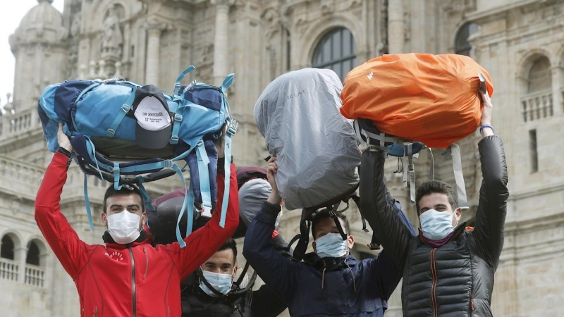 13/03/2020.- Peregrinos muestran sus mochilas mientras se protegen con mascarillas al terminar el Camino a pesar de la crisis del coronavirus. / EFE - LAVANDEIRA JR