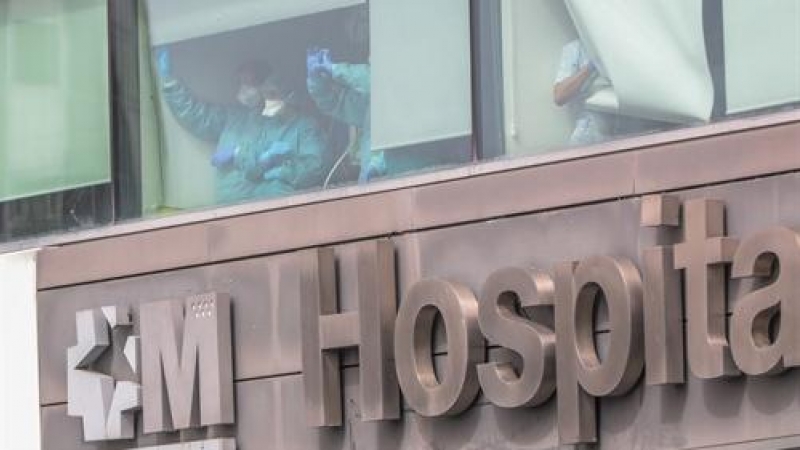 Sanitarios del Hospital de La Paz totalmente protegidos saludan y agradecen el apoyo desde una de las ventanas del centro donde se lucha contra el coronavirus, en Madrid (España)