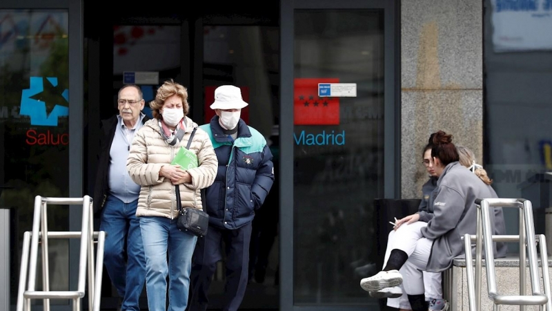 Dos personas mayores con mascarillas caminan junto a la entrada del hospital La Paz de Madrid. - EFE