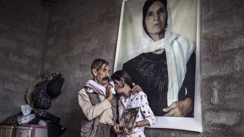 Xelef, padre de Sharihan, trata de consolarla frente a un retrato de su madre, asesinada por el Estado Islámico, en una habitación de su casa en Sinune. JM LÓPEZ