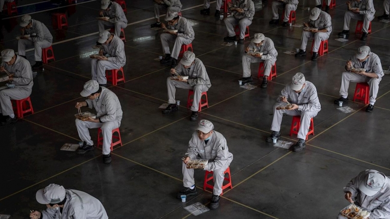 Trabajadores de una fábrica de Wuhan (China) comen sentados a un metro y medio de distancia. La ciudad comienza poco a poco a recuperar la normalidad. /EFE