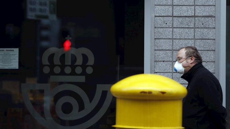 Una hombre protegido con mascarilla espera entrar en Correos, en Bilbao. - EFE