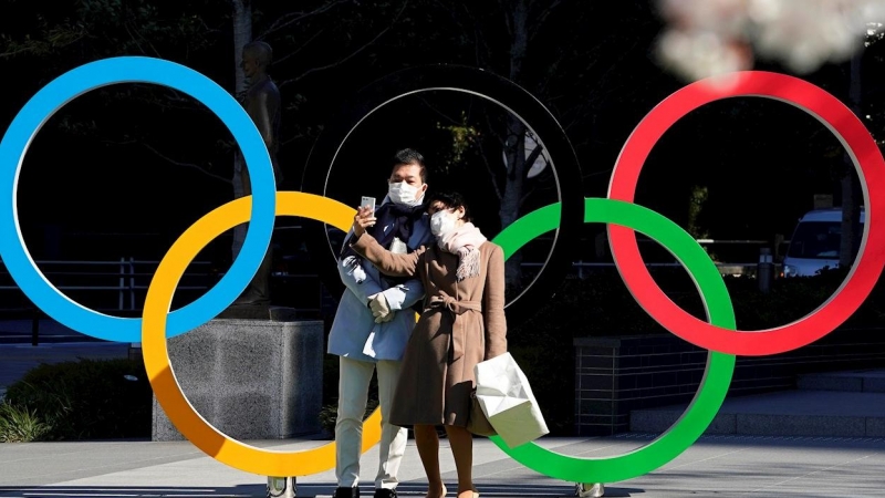 24/03/2020.- Una pareja con mascarillas se hace fotos frente a la sede del Comité Olímpico de Japón en Tokio. / EFE - FRANCK ROBICHON