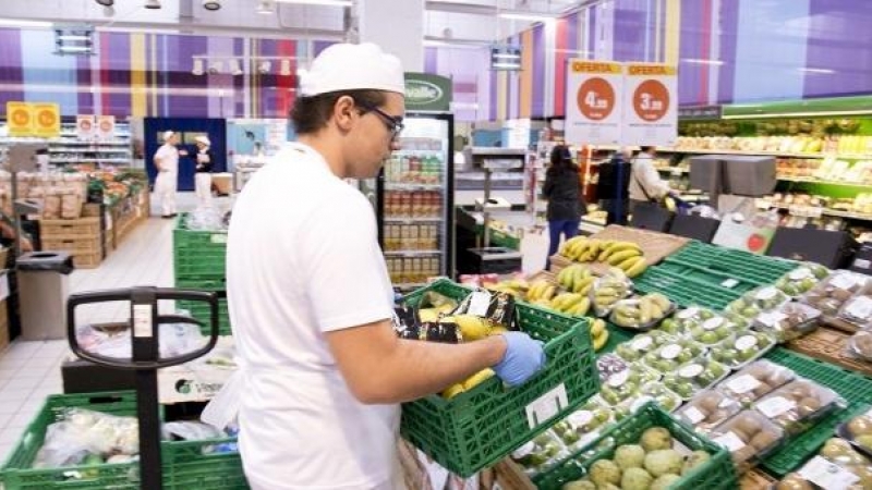 Un empleado repone fruta en un supermercado