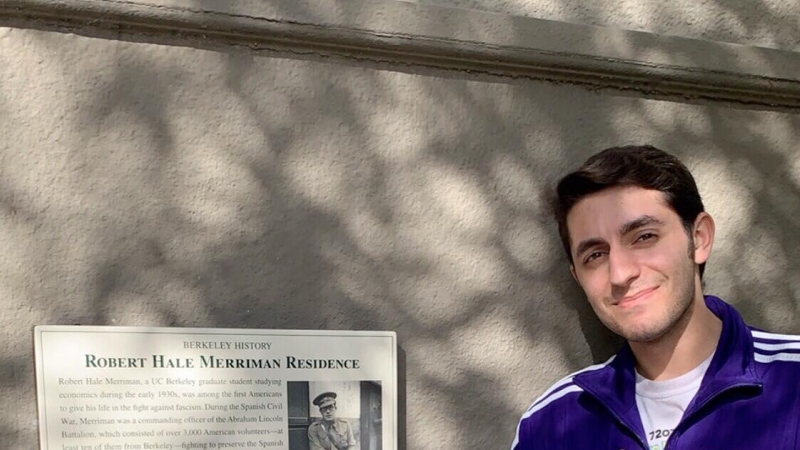 Milton Zerman posa junto a la placa conmemorativa de Robert Merriman colocada en la fachada del antiguo hogar de los Merriman en Berkeley.