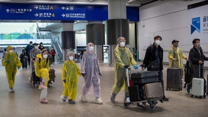 Viajeros llegan al aeropuerto internacional de Hong Kong provistos de trajes de aislamiento y mascarillas. /EFE