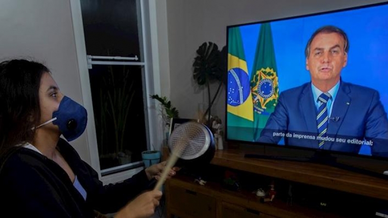 Una mujer con una máscarilla protesta golpeando una olla durante una declaración televisda del presidente de Brasil, Jair Bolsonaro, este martes en Brasilia (Brasil). EFE/Joédson Alves