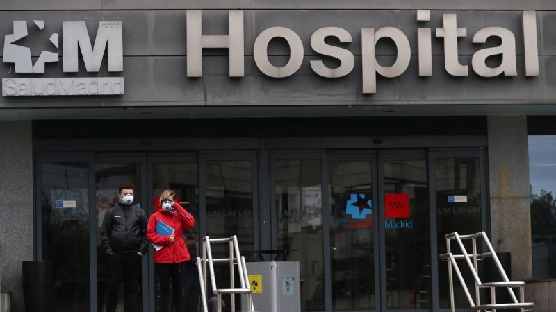 Dos personas con mascarilla, en el exterior de un hospital en Madrid. REUTERS